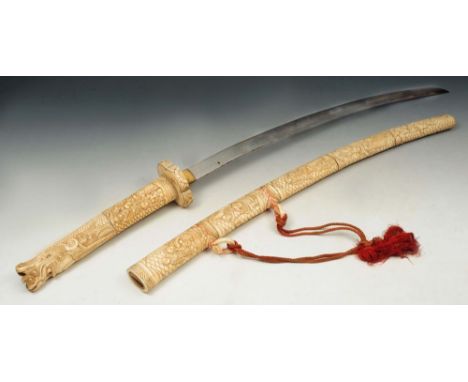 A Japanese carved ivory mounted sword hilt and scabbard, the hilt terminating in a dragon head with scrolled clouds, the hilt