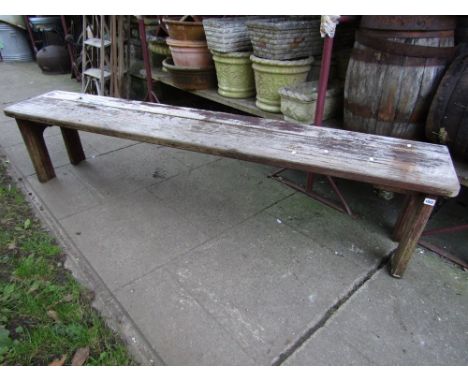 A weathered teak garden bench with planked seat raised on shaped and moulded supports, 83 inches long approx