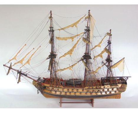 A scale model of a three mast battle ship fitted with canons and sails.