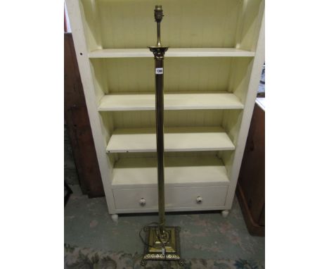 A traditional brass lamp standard with reeded column, raised on a stepped base with lions paw feet