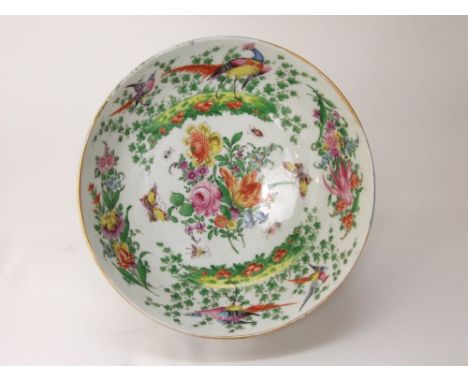 A 19th century punch or fruit bowl in the 18th century manner with blue scale ground and painted floral and bird cartouche to