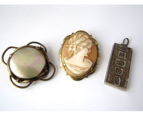 A yellow metal mother of pearl brooch together with a silver ingot pendant and a cameo brooch