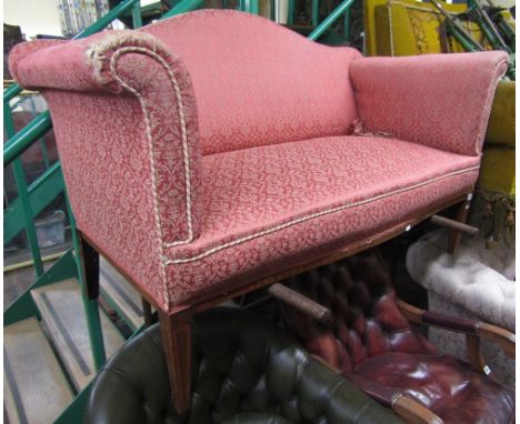 An Edwardian two seat sofa with swept arms, arched back, and serpentine seat, with floral patterned upholstery on a rose colo