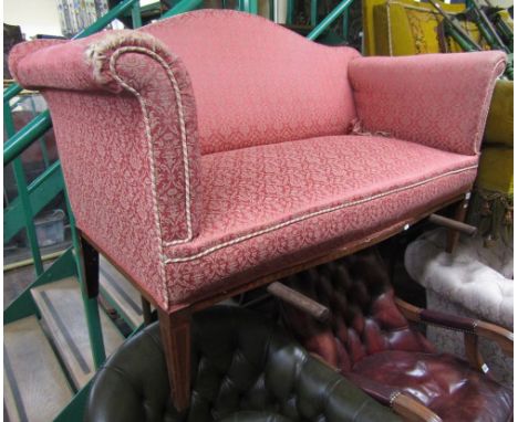 An Edwardian two seat sofa with swept arms, arched back, and serpentine seat, with floral patterned upholstery on a rose colo