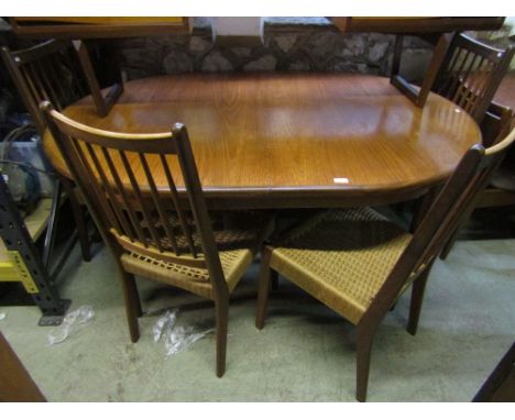 A Danish style extending teak oval dining table together with a set of four teak stick back dining chairs with Danish strung 