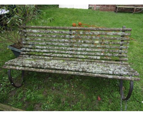 A three seat garden bench with weathered timber slatted seat and combined back rasied on scrolled steel supports, 6ft long