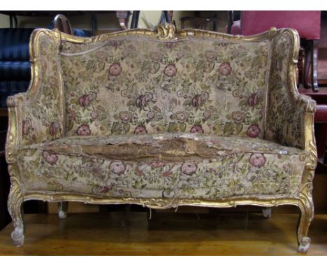 A 19th century two seat salon sofa, with serpentine upholstered seat, back and arms, within a shaped carved and moulded gilde