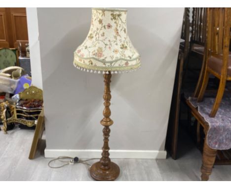 Heavily carved oak based pedestal standard lamp with fringed floral patterned shade