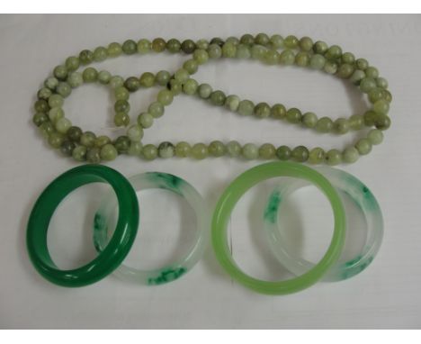 Four jade bangles and a bead necklace