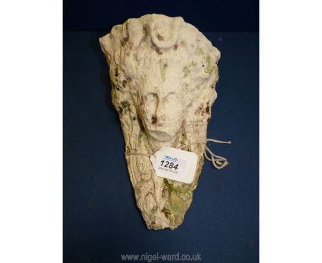 A small weathered carved face architectural item.