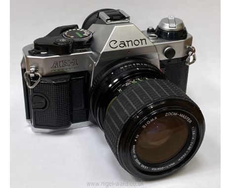 A Canon AE-1 Program 35mm SLR camera with a Sigma Zoom-Master 35-70mm f/2.8-4 lens, kamkit gadget case, lanyard and a small C