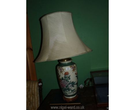 A Chinese lamp in gilded flower pattern with a wooden base and white shade.