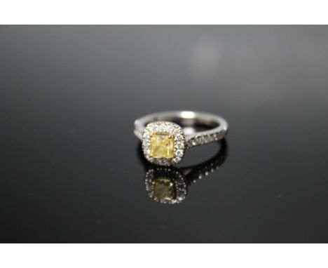 A HALLMARKED PRINCESS CUT YELLOW DIAMOND PLATINUM RING, the central claw set yellow diamond is of good colour and is surround