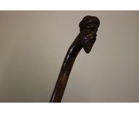 A WALKING STICK CARVED WITH A MAN'S HEAD WEARING EASTERN STYLE HEADDRESS, L 88 cm