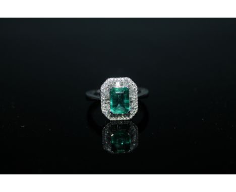 A HALLMARKED 18 CARAT WHITE GOLD EMERALD AND DIAMOND RING,  the central emerald cut emerald of approx 1.33 carats is surround