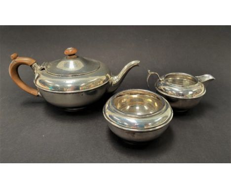 A George V silver three piece batchelor tea set by Charles and Richard Comyns, comprising a squat ovoid teapot with fruitwood