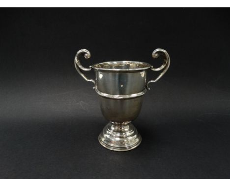 A silver hallmarked pedestal trophy cup with flying scroll handles, engraved dedication, height 12cm (hallmarks rubbed), weig