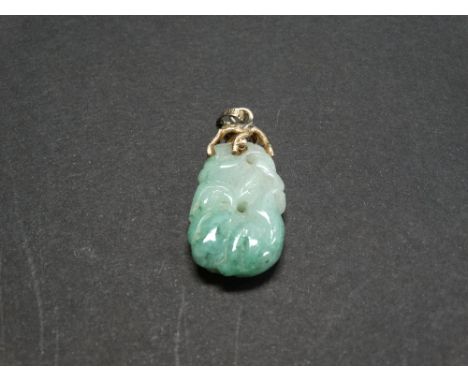 A 14ct. gold mounted jade pendant carved with a crouching monkey amongst foliage and with naturalistic gold twig mount with l