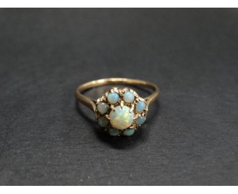 A 9ct. gold opal set nine stone cluster ring, the central cabochon opal of 0.33ct. spread approx., stamped 9ct, weight 2.3g a