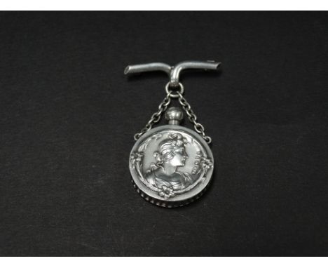 An attractive Art Nouveau silver pendant scent bottle on chain hanging on a bar brooch, each side of the circular bottle embo