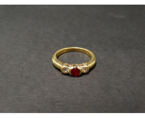 A modern 18ct hallmarked gold, diamond and ruby three stone ring, the central ruby of 0.25ct spread approx., the diamonds of 