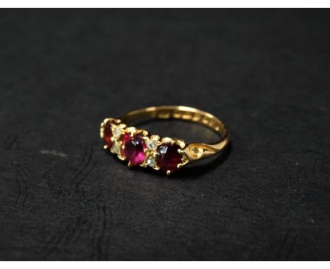 An attractive Edwardian 18ct. gold diamond and ruby seven stone ring, the central oval ruby measuring 0.20ct approx., flanked