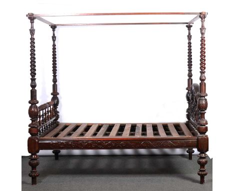 Anglo-Indian carved hardwood four-poster bed, the canopy supported by barleytwist uprights with carved caps, the headboard el