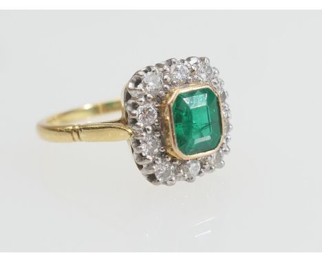 Emerald and diamond cluster ring, the emerald of approx. 1ct, collet set in yellow gold and bordered with ten round cut diamo