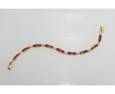 Ruby and diamond line bracelet, set with nine bar links channel set with three oval cut rubies dispersed with round brilliant