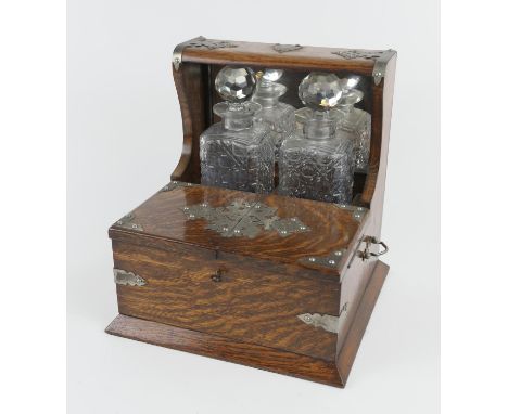 Victorian oak tantalus, with nickel mounts, two moulded glass spirit decanters and opening covers to reveal compartments for 