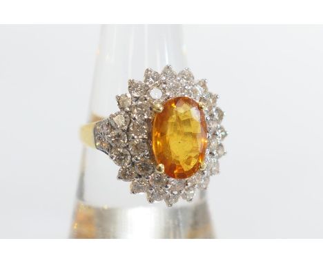 Orange gemstone and diamond cluster ring, the central orange stone approx. 11mm x 8mm, in a four claw mount, bordered with tw
