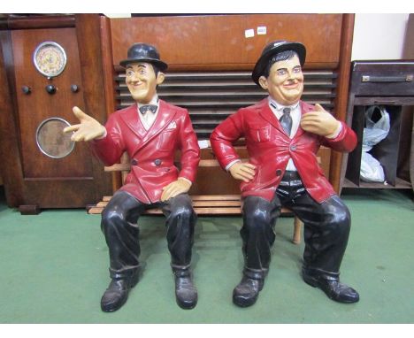 A set of Laurel and Hardy figures seated on wooden bench, 62cm tall