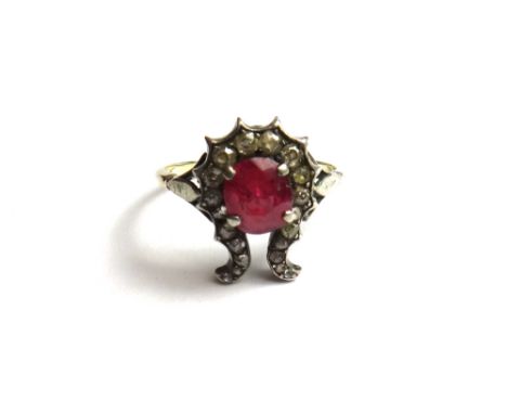 A gold and silver, ruby and diamond set ring, mounted with the cushion shaped ruby at the centre within an open ended surroun