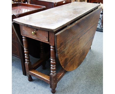 A 17th century oak drop flap dining table with end frieze drawer, on bobbin turned supports, 130cm wide.