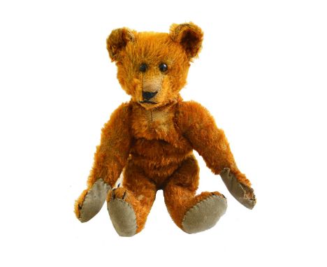 A Steiff teddy bear, circa 1910, with boot button eyes, hand stitched snout, plush orange fur, hump back, and jointed limbs, 