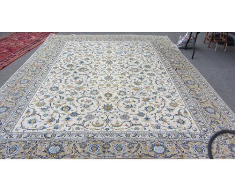 A Tabriz carpet, Persian, the ivory field with an allover trailing foliate vine design, a beige border with palmettes and tra