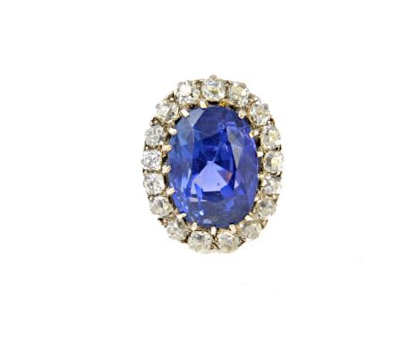 A white gold, sapphire and diamond set oval cluster ring, claw set with the large oval cut sapphire at the centre, within a s