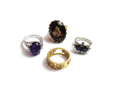 A gold ring, claw set with an oval cut smoky quartz, a white gold ring, claw set with two oval cut sapphires and with eight s