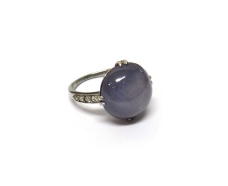 A star sapphire and diamond set ring, claw set with the circular star sapphire cabochon at the centre, between diamond set fo