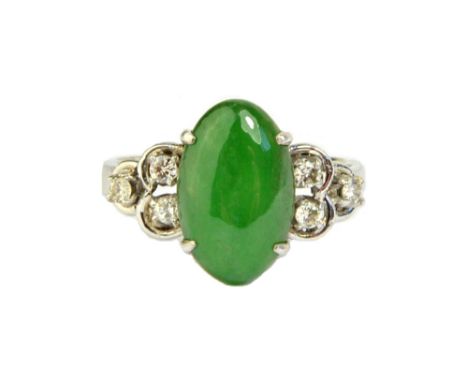 A white gold ring, claw set with an oval jade cabochon at the centre, between diamond set three stone shoulders, mounted with