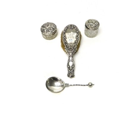 Two silver lidded faceted glass circular toilet jars, the covers decorated with cherub's faces, a silver spoon, having a spir