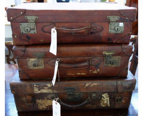 A heavy leather vintage suitcase with gilt metal hardware, stamped 'G P Cross' to the lid, 62cm wide, together with two simil