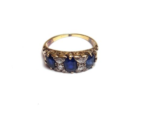 A gold, sapphire and diamond set ring, mounted with three oval cut sapphires and with two pairs of cushion shaped diamonds mo