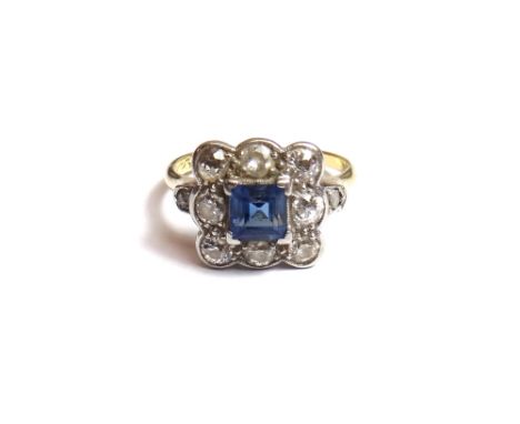 A gold and platinum, diamond and sapphire set nine stone square cluster ring, claw set with the square emerald cut sapphire a