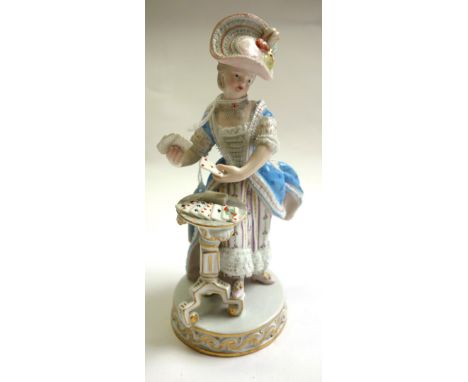 A Meissen porcelain figure, 19th century, modelled as a lady in a blue dress, after the model by Acier, standing at a table w