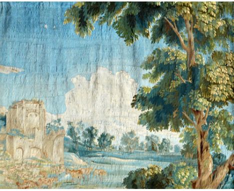 An early 18th century Flemish tapestry fragment depicting ruins and cattle in a wooden landscape, suspended on an iron bracke