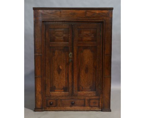 A George III oak inlaid hanging corner cupboard, circa 1760, the two cupboard doors with geometric mouldings, enclosing shelf