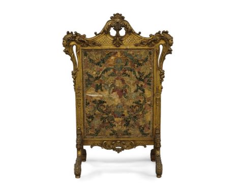 A large French giltwood fire screen, 19th century, with central silk stump work panel, below carved C scroll crest and basket