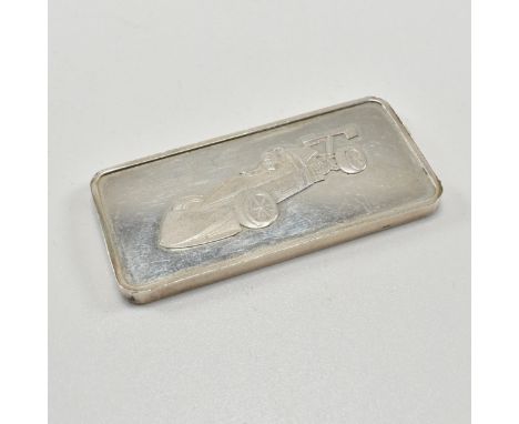 A hallmarked silver ingot. The ingot is hallmarked for Birmingham date letter c for 1977. Depiction of race car to front and 