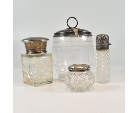 A collection of four hallmarked silver topped glassware. To include a cut glass scent bottle with hinged hallmarked silver li